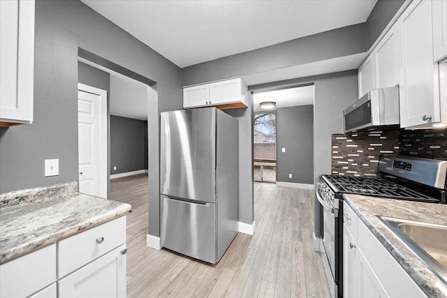 kitchen featuring backsplash, light wood-type flooring, white cabinetry, and stainless steel appliances