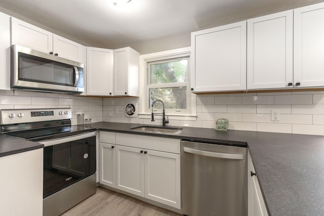 kitchen with backsplash, sink, white cabinets, and appliances with stainless steel finishes