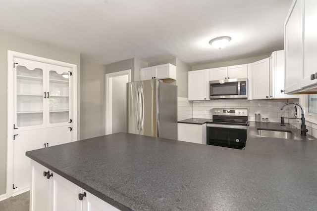 kitchen with stainless steel appliances, white cabinetry, tasteful backsplash, and sink