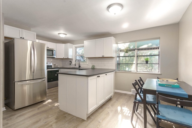 kitchen with tasteful backsplash, light hardwood / wood-style flooring, white cabinets, and appliances with stainless steel finishes