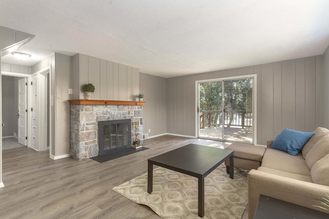 living room with a stone fireplace and wood-type flooring