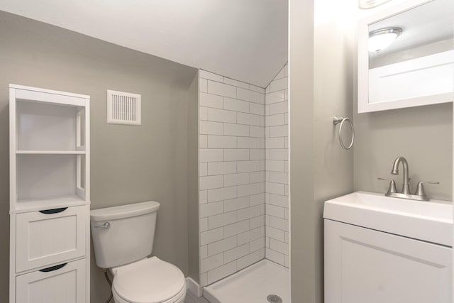 bathroom with vanity, toilet, and tiled shower