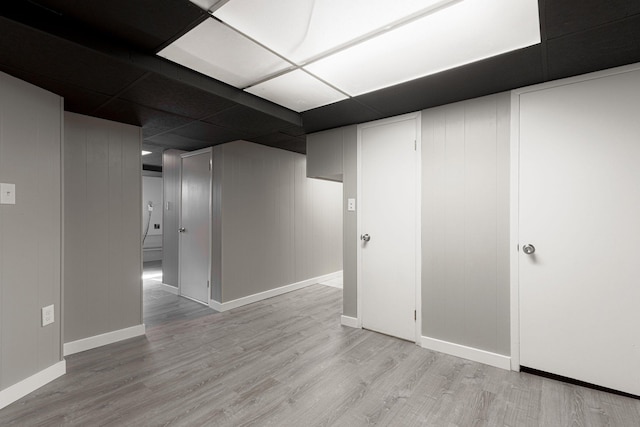 basement featuring a drop ceiling and light hardwood / wood-style floors