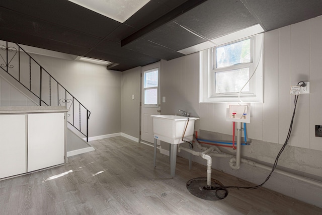 basement with sink, a drop ceiling, and light wood-type flooring