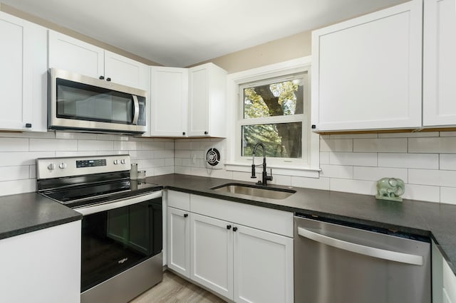 5721 Corunna Ave, Clarkston, MI 48346 - kitchen featuring stainless steel appliances, a sink, dark countertops, white cabinetry, and decorative backsplash