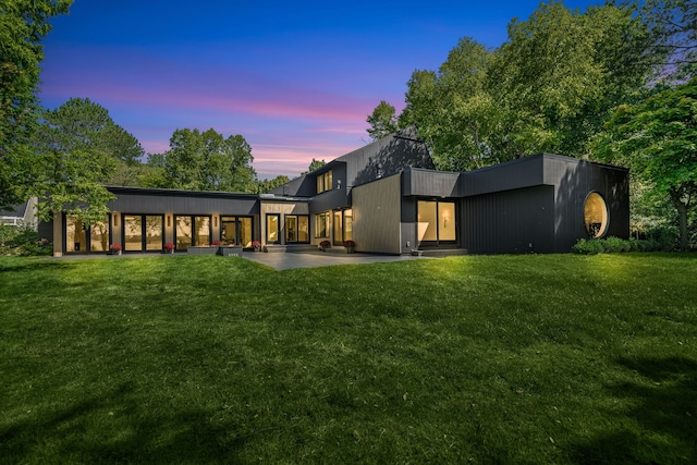 back house at dusk featuring a yard