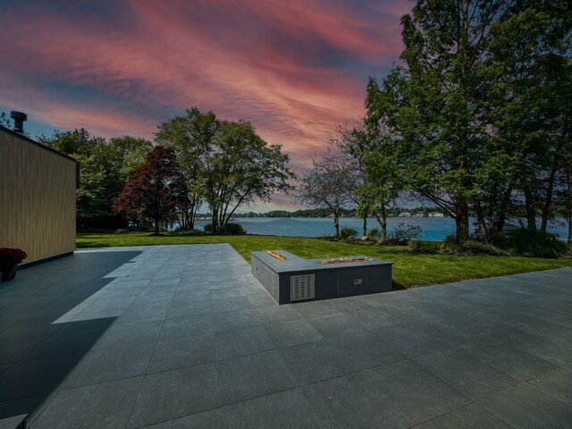 view of home's community with an outdoor fire pit, a patio, a lawn, and a water view