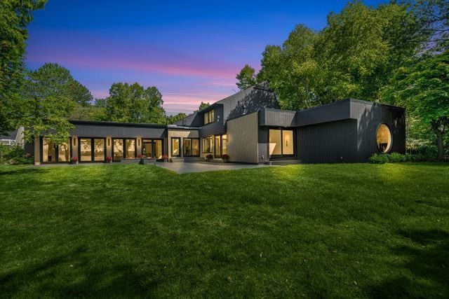 back house at dusk with a lawn