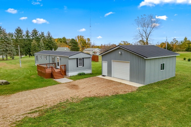 rear view of property featuring a lawn, a wooden deck, an outbuilding, and a garage