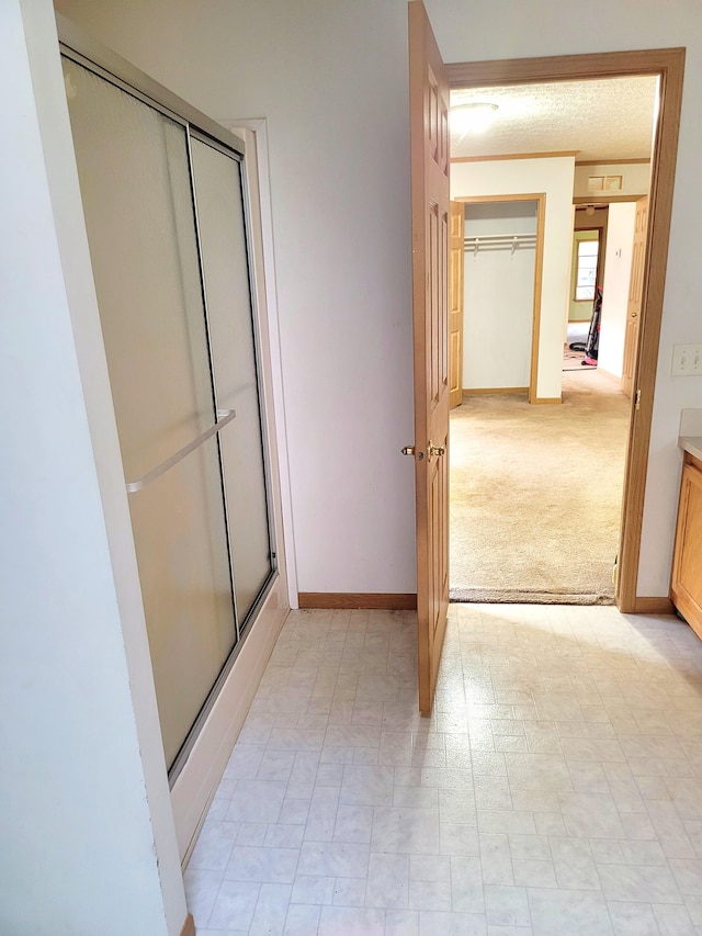 full bath with a closet, a shower with shower door, baseboards, and tile patterned floors