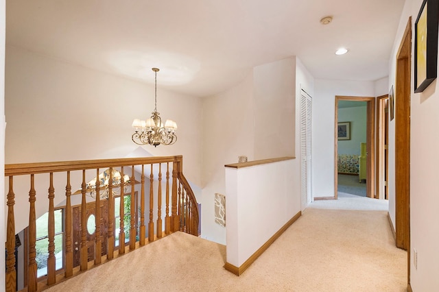 hallway with light carpet and a notable chandelier