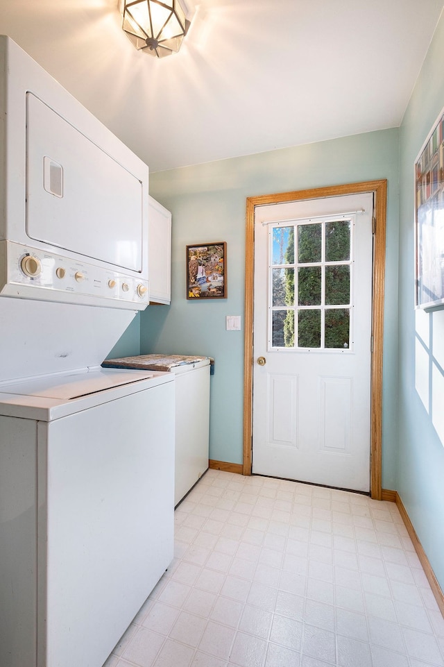 laundry area with stacked washer / dryer and cabinets