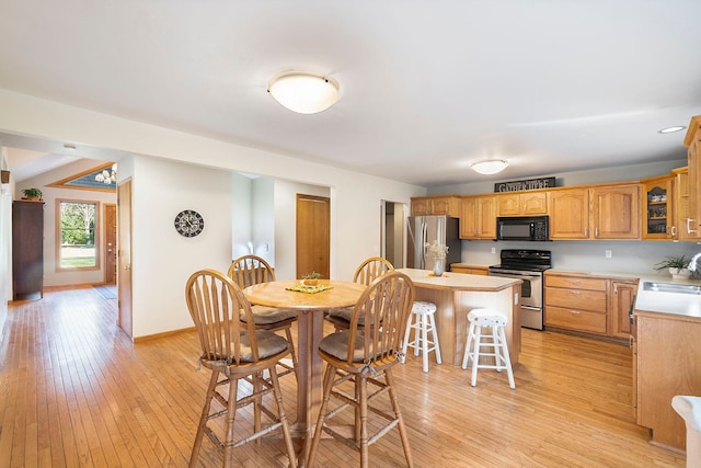 kitchen with a center island, sink, stainless steel appliances, a kitchen breakfast bar, and light hardwood / wood-style flooring