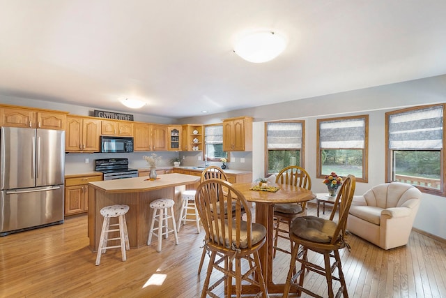 kitchen featuring black appliances, plenty of natural light, light hardwood / wood-style floors, and a kitchen island