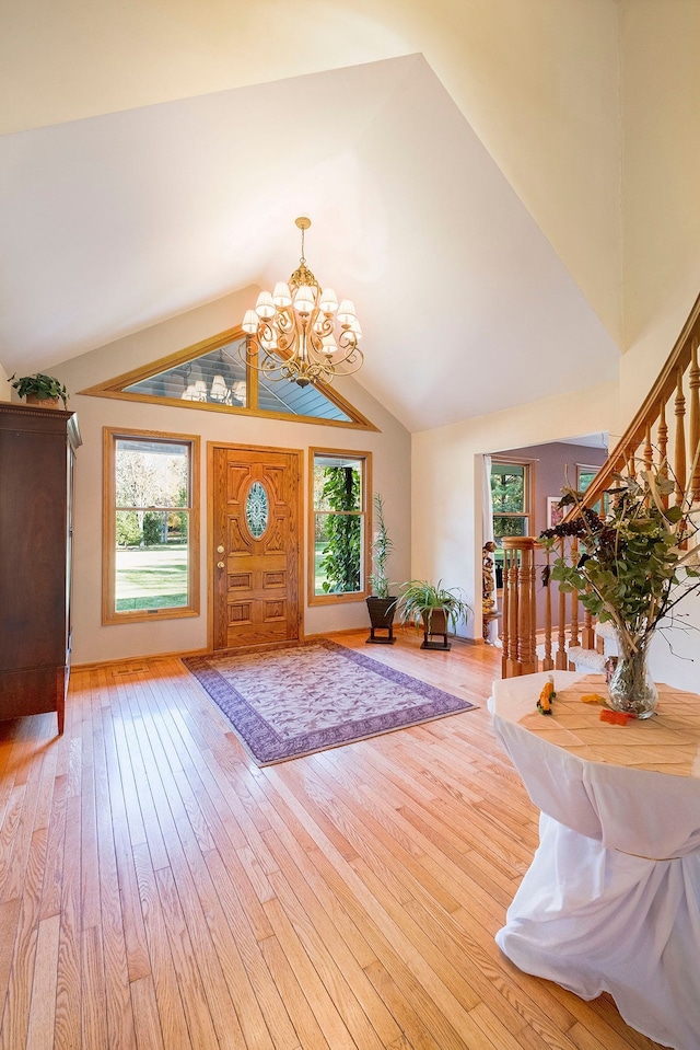 entryway with a notable chandelier, plenty of natural light, light wood-type flooring, and lofted ceiling