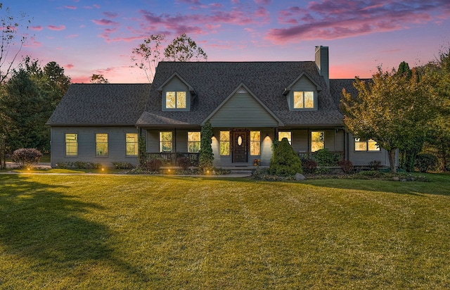 cape cod-style house featuring a lawn and a porch