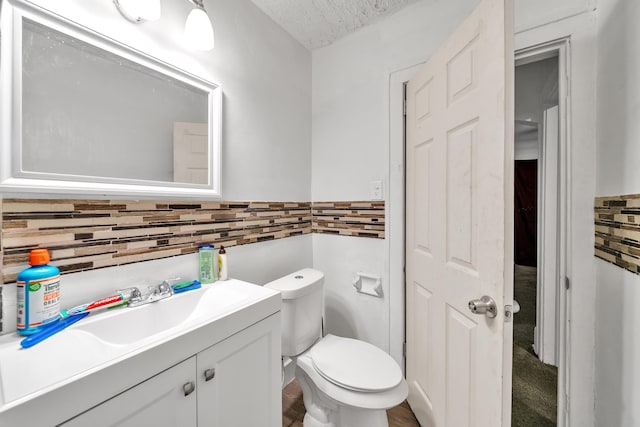 bathroom with vanity, toilet, and a textured ceiling