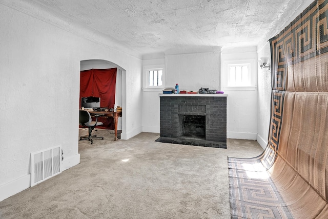 living room with carpet flooring, a textured ceiling, and a brick fireplace