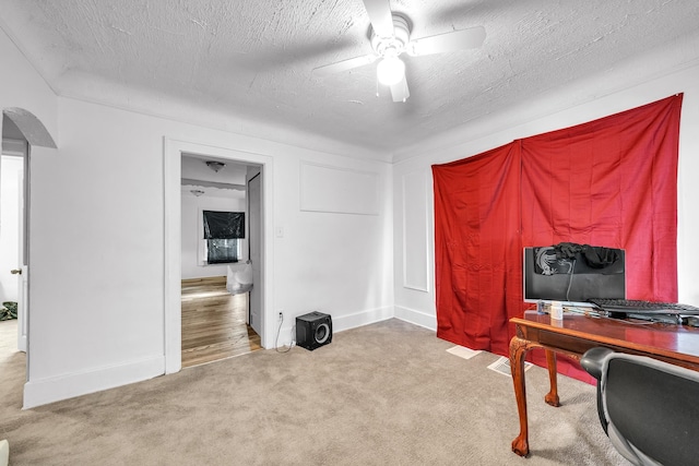 office area featuring a textured ceiling, light colored carpet, and ceiling fan