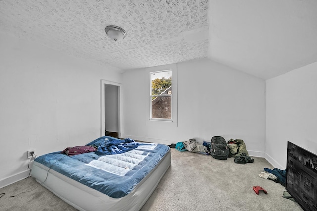 carpeted bedroom featuring a textured ceiling and vaulted ceiling