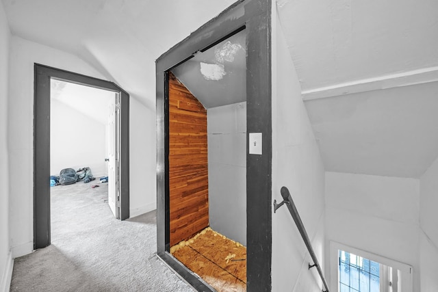 corridor featuring carpet flooring, wood walls, and vaulted ceiling