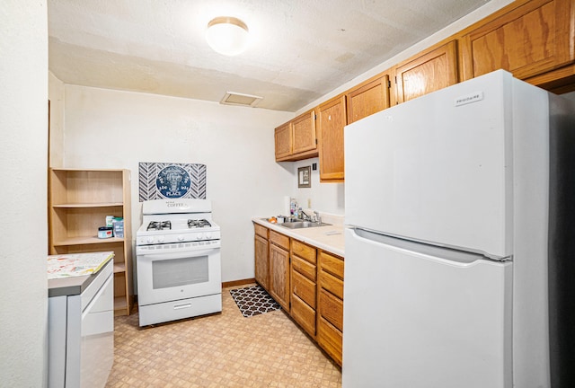 kitchen with a textured ceiling, white appliances, and sink