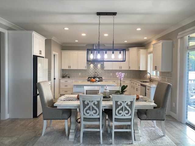 kitchen with pendant lighting, dishwasher, sink, white cabinets, and a center island