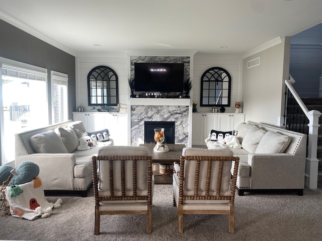 carpeted living room featuring crown molding and a premium fireplace