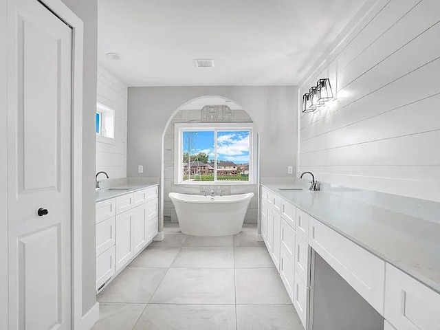 bathroom with tile patterned flooring, vanity, and a washtub