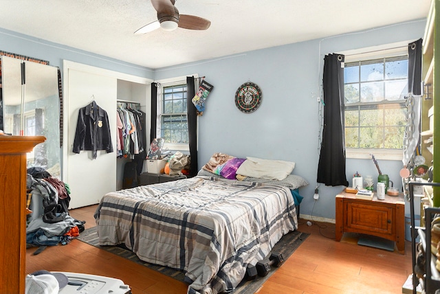 bedroom with a closet, multiple windows, ceiling fan, and light hardwood / wood-style flooring