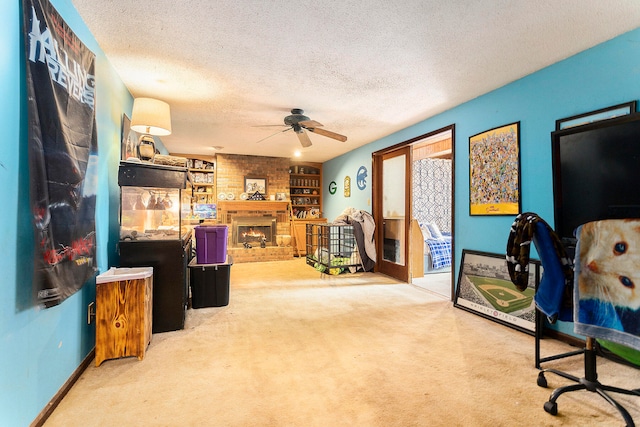 carpeted office space featuring a textured ceiling, a brick fireplace, and ceiling fan