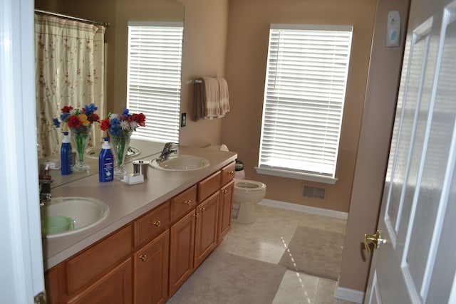 bathroom with tile patterned flooring, vanity, toilet, and a healthy amount of sunlight