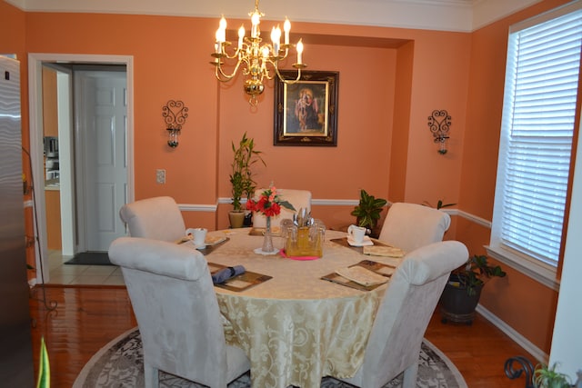 dining space with a notable chandelier, wood-type flooring, and ornamental molding