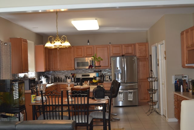 kitchen featuring pendant lighting, an inviting chandelier, light tile patterned floors, tasteful backsplash, and stainless steel appliances