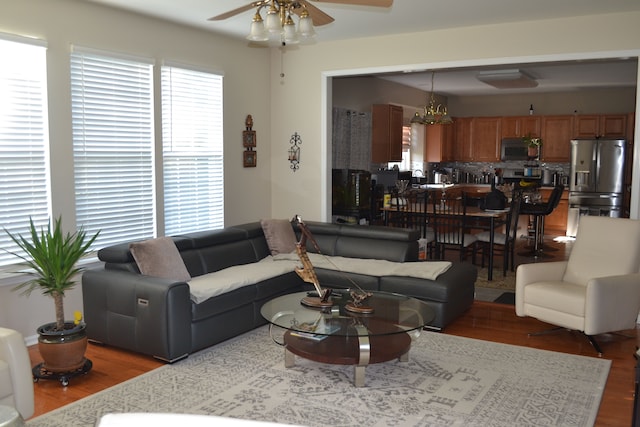 living room with ceiling fan with notable chandelier and dark hardwood / wood-style floors