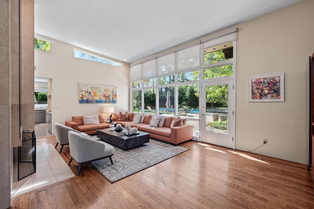 living room with french doors, high vaulted ceiling, a healthy amount of sunlight, and light hardwood / wood-style floors