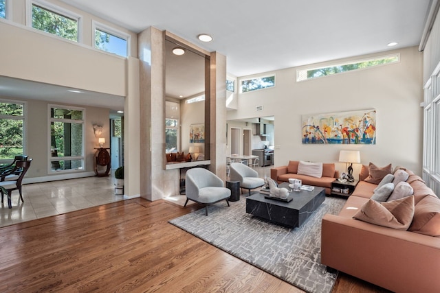 living room with wood-type flooring and a towering ceiling