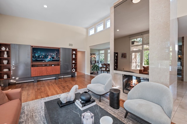 living room featuring plenty of natural light, light hardwood / wood-style floors, and a towering ceiling