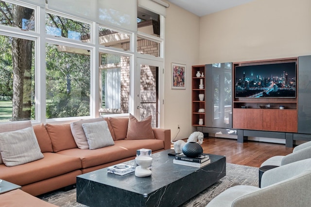 living room with hardwood / wood-style floors and a towering ceiling