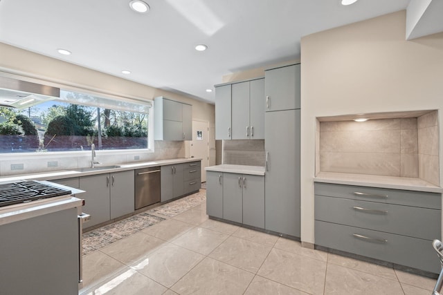 kitchen featuring stainless steel dishwasher, gray cabinets, sink, and tasteful backsplash