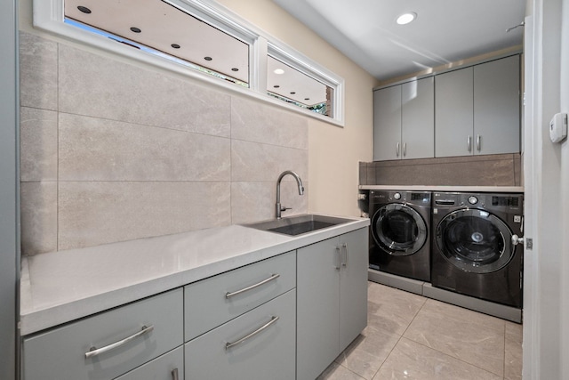 washroom with light tile patterned flooring, cabinets, sink, and washing machine and clothes dryer