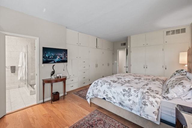 bedroom featuring connected bathroom and light hardwood / wood-style flooring