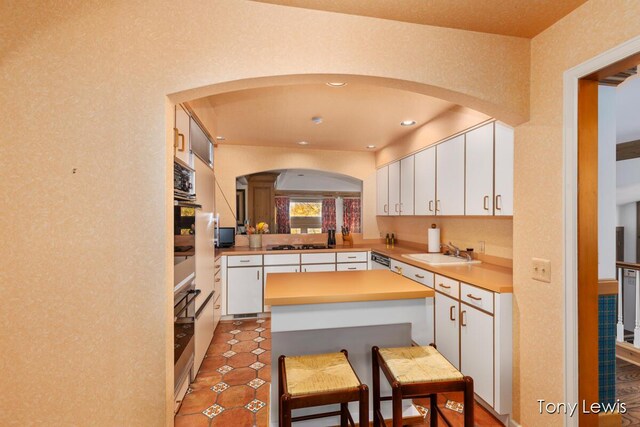 610 Cascade Hills Holw SE, Grand Rapids, MI 49546 - kitchen featuring arched walkways, a sink, a kitchen island, black stovetop, and recessed lighting