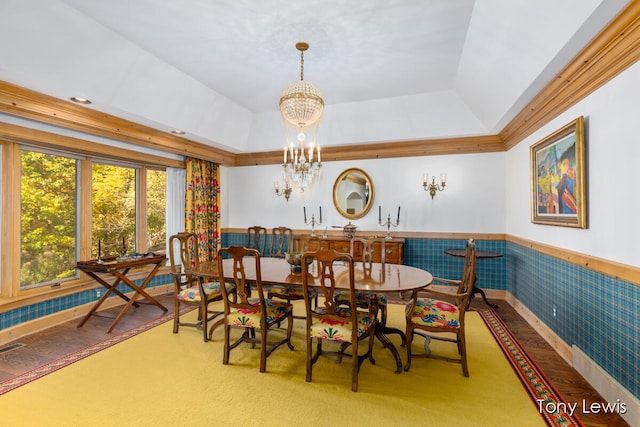 carpeted dining room featuring an inviting chandelier and a raised ceiling