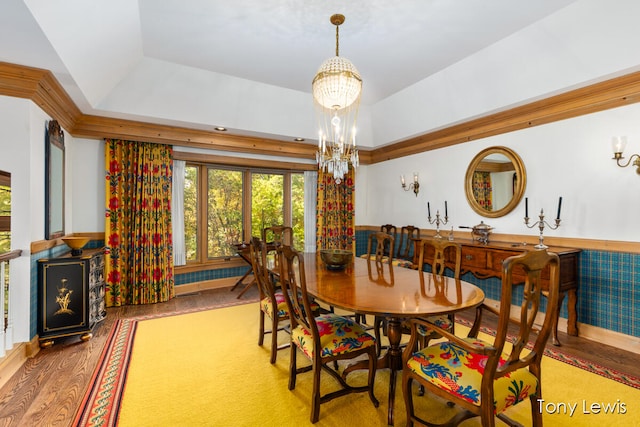 dining room with hardwood / wood-style floors, an inviting chandelier, and a raised ceiling