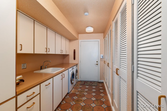 kitchen with a textured ceiling, dark tile patterned floors, sink, white cabinets, and washing machine and dryer