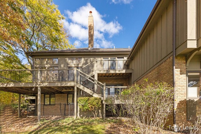 610 Cascade Hills Holw SE, Grand Rapids, MI 49546 - rear view of house with brick siding, stairs, a wooden deck, and board and batten siding