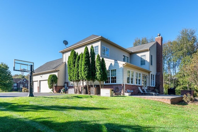 rear view of house with a yard and a garage