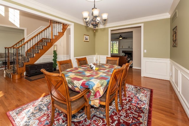 dining space featuring hardwood / wood-style floors, ceiling fan with notable chandelier, and crown molding