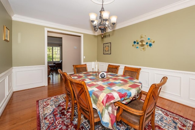 dining area featuring crown molding, dark wood-type flooring, and an inviting chandelier